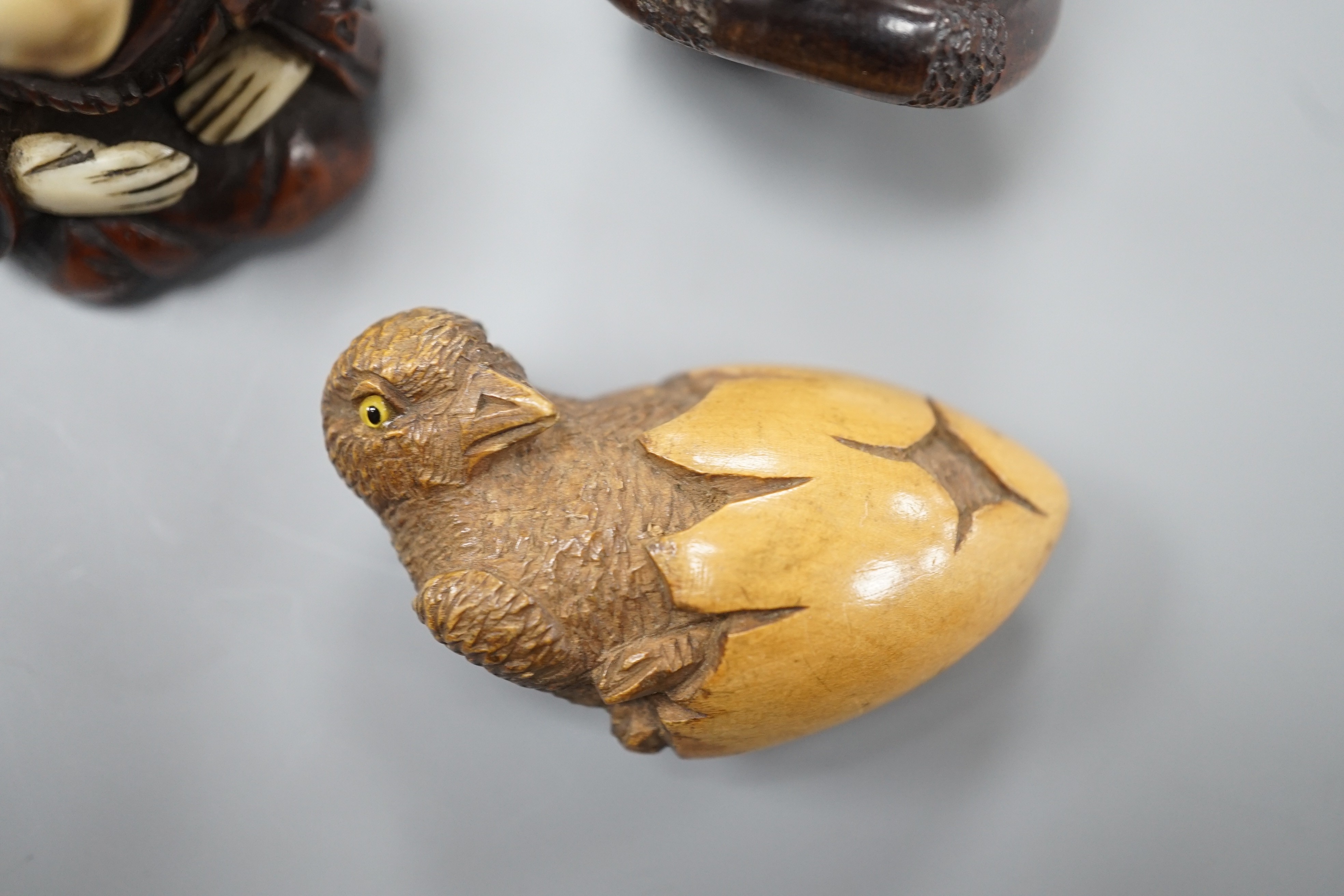 A Continental wood ‘chick and egg’ brooch ivory, 5.3cm, a Japanese ivory and wood figure and a wood netsuke of snakes (3)